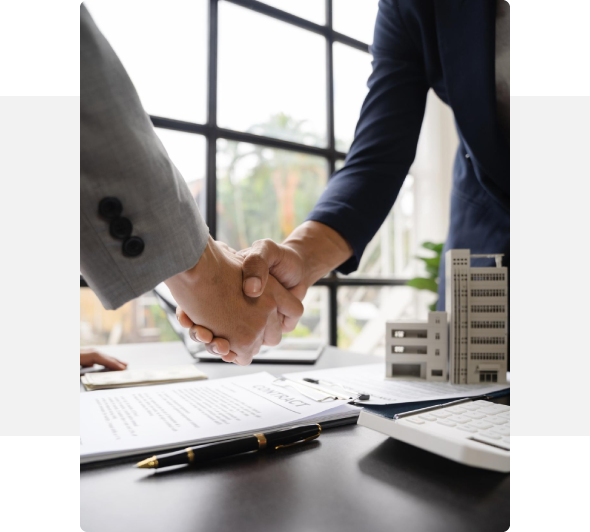 dos personas estrechándose la mano con papeles en la mesa