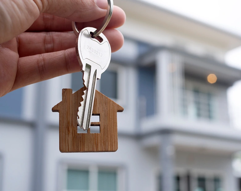 mano en primer plano sujetando llavero con forma de casa